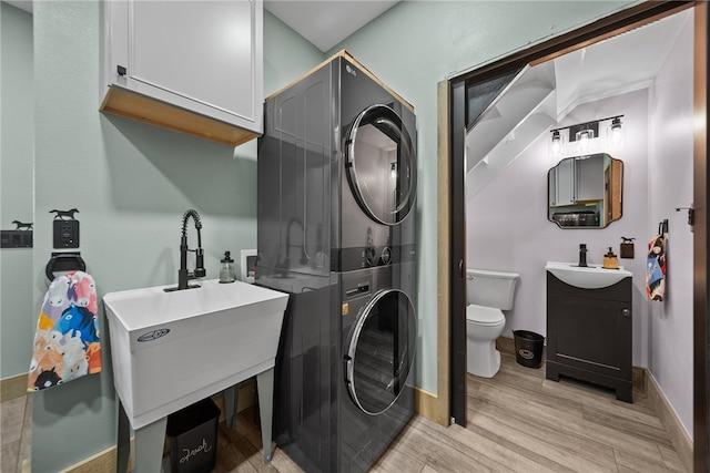 washroom with sink, light hardwood / wood-style floors, and stacked washer / dryer