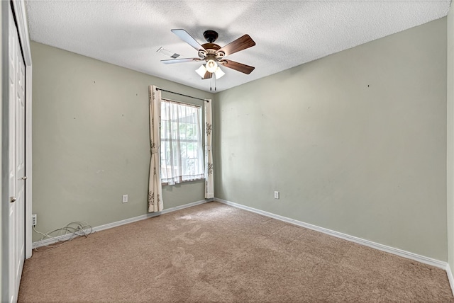 spare room with ceiling fan, light carpet, and a textured ceiling