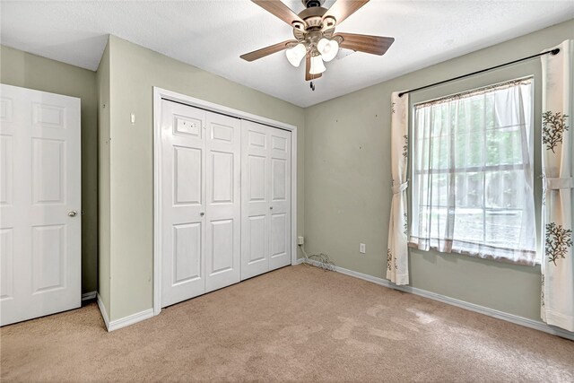 unfurnished bedroom with a closet, ceiling fan, light carpet, and a textured ceiling