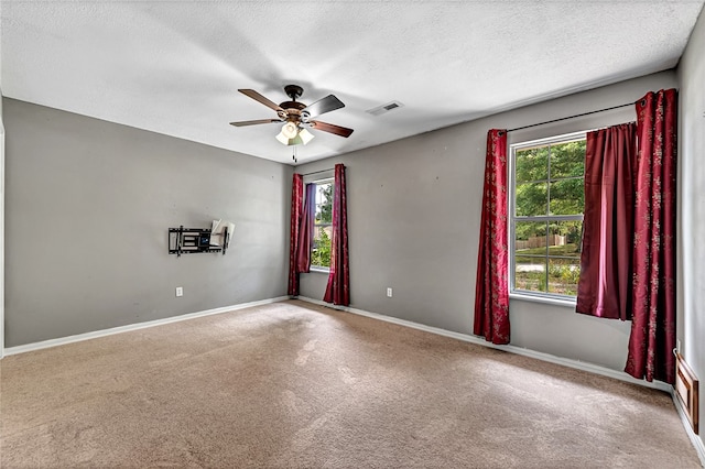 unfurnished room featuring ceiling fan, carpet, a textured ceiling, and a healthy amount of sunlight