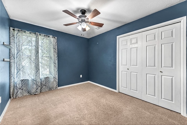 unfurnished bedroom with carpet flooring, a textured ceiling, ceiling fan, and a closet