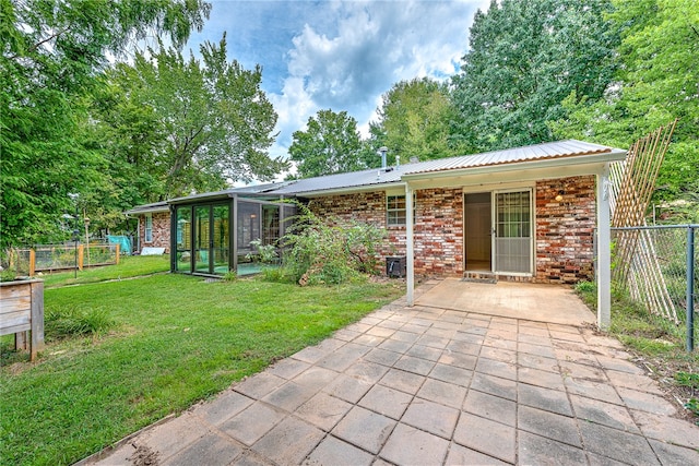 exterior space with a sunroom, a front yard, and a patio