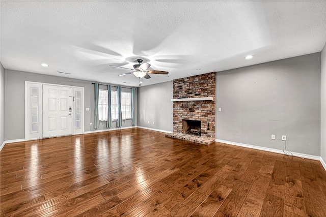 unfurnished living room featuring a fireplace, a textured ceiling, hardwood / wood-style floors, and ceiling fan