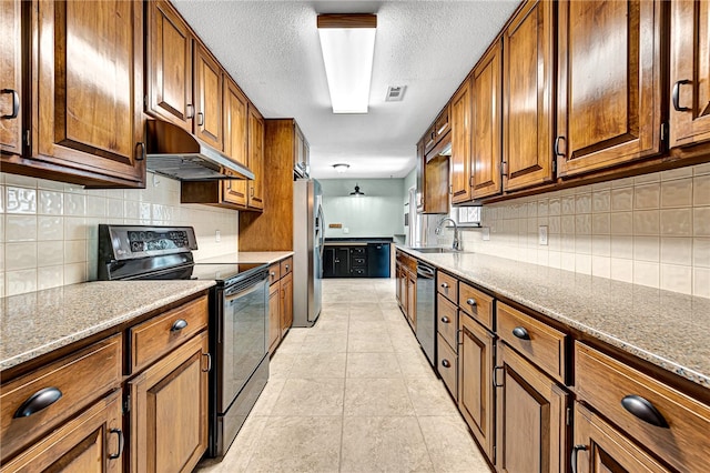 kitchen featuring a textured ceiling, light stone counters, sink, appliances with stainless steel finishes, and extractor fan