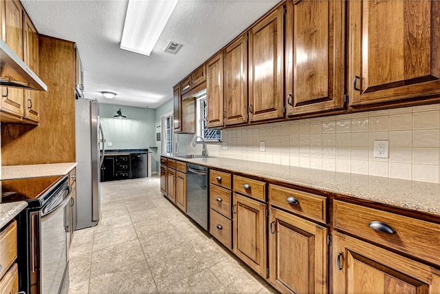 kitchen with light stone counters, sink, appliances with stainless steel finishes, and decorative backsplash