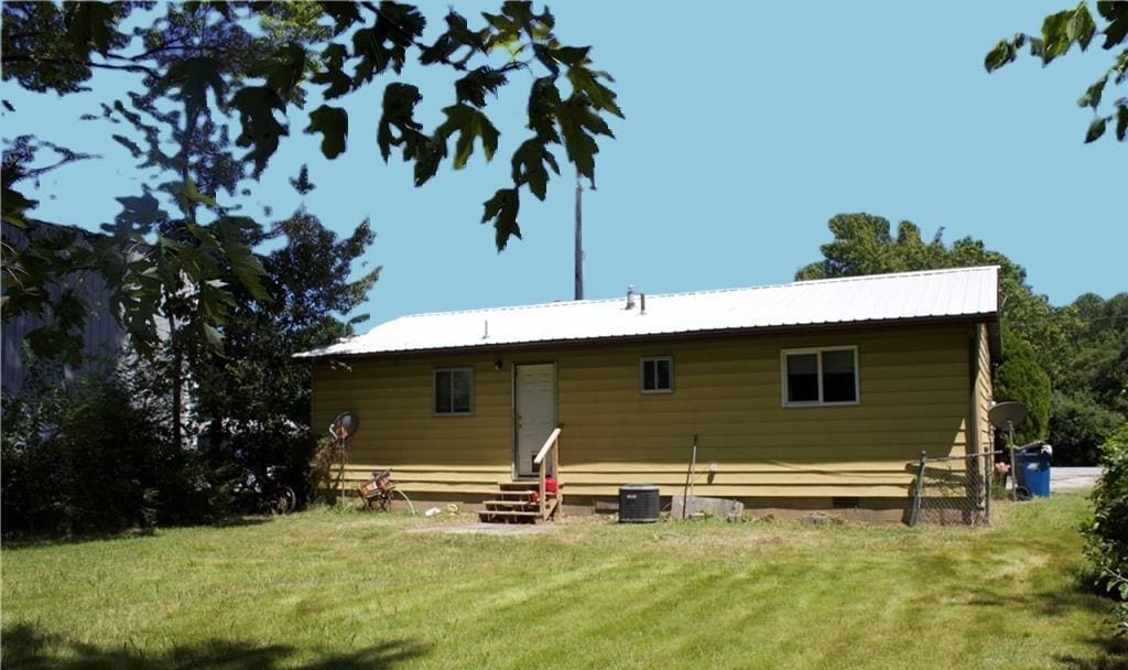 1116 S Main St, Bentonville, AR 72712 - back of property with entry steps, a lawn, crawl space, central AC unit, and metal roof