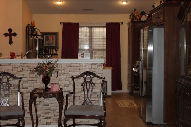 kitchen featuring a stone fireplace, dark hardwood / wood-style floors, stainless steel fridge, and dark brown cabinetry