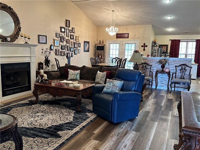 living room with vaulted ceiling, dark hardwood / wood-style flooring, a healthy amount of sunlight, and a chandelier