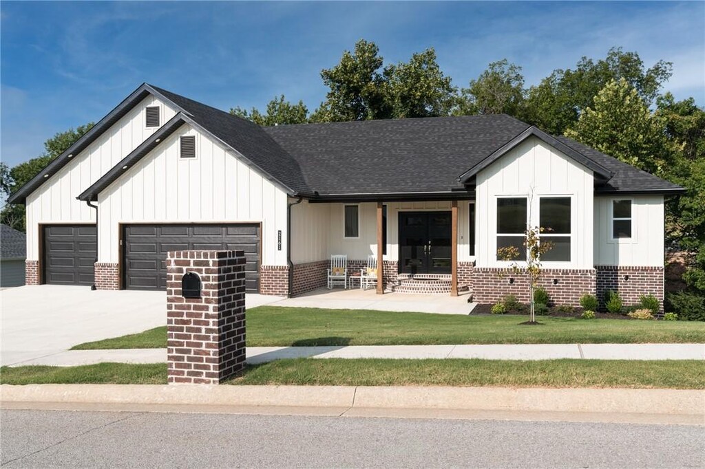 modern farmhouse style home with covered porch, a garage, and a front yard