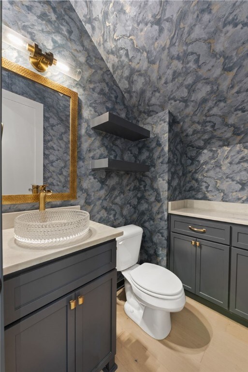 bathroom featuring wood-type flooring, toilet, and vanity