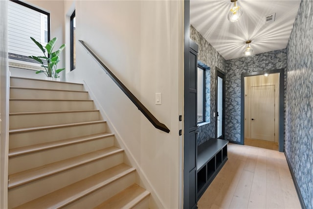 stairs with a healthy amount of sunlight and hardwood / wood-style floors