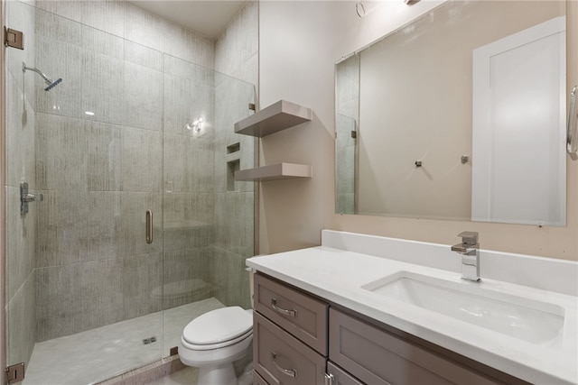 bathroom with vanity, toilet, and a shower with door