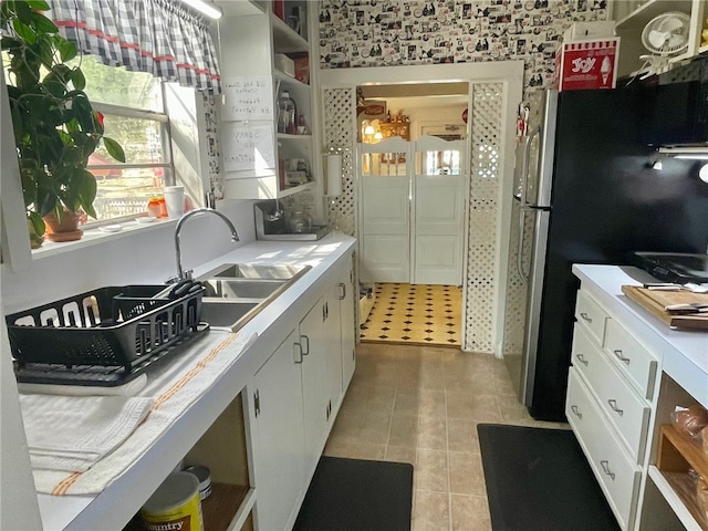 kitchen with light tile patterned floors, white cabinetry, and sink