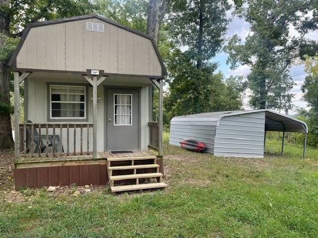 view of outdoor structure with a lawn, a carport, and a porch