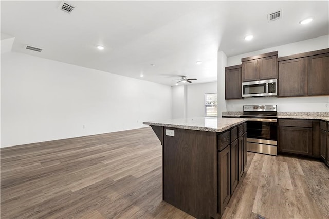 kitchen featuring a kitchen island, dark brown cabinets, stainless steel appliances, ceiling fan, and light wood-type flooring