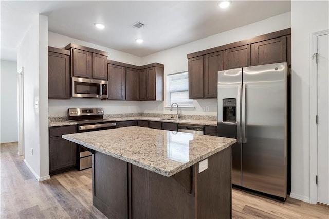 kitchen with a breakfast bar area, light hardwood / wood-style flooring, a center island, stainless steel appliances, and sink