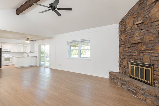 unfurnished living room with a stone fireplace, ceiling fan, light hardwood / wood-style floors, beamed ceiling, and sink