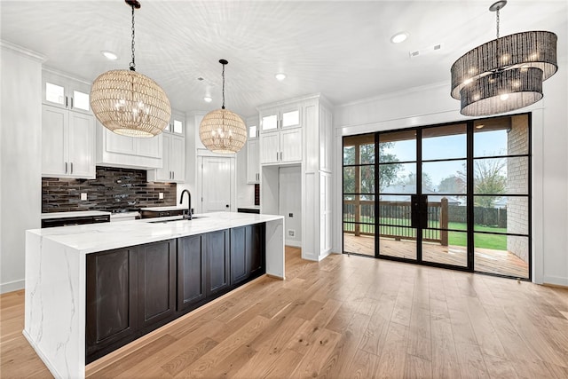 kitchen with white cabinetry, hanging light fixtures, an inviting chandelier, and crown molding