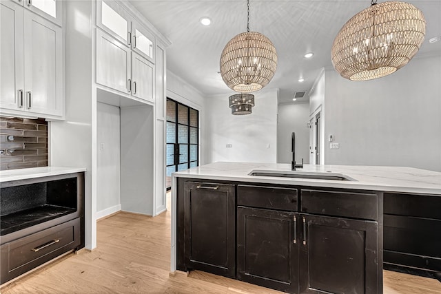 kitchen featuring a notable chandelier, sink, tasteful backsplash, hanging light fixtures, and white cabinetry