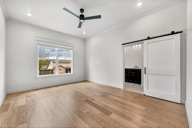 unfurnished living room with crown molding, light hardwood / wood-style floors, a barn door, and ceiling fan