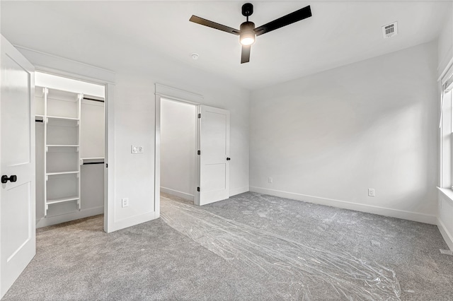 unfurnished bedroom with light colored carpet, ceiling fan, a spacious closet, and a closet