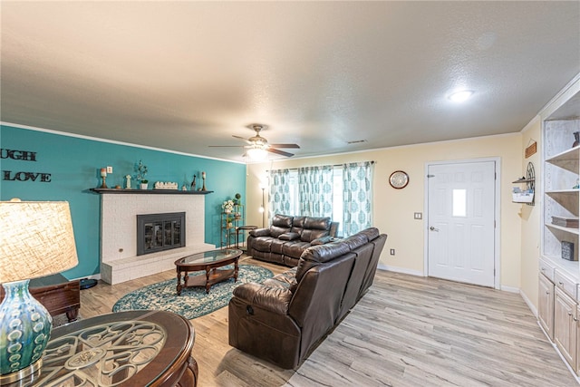 living room with ornamental molding, light hardwood / wood-style floors, ceiling fan, and a textured ceiling