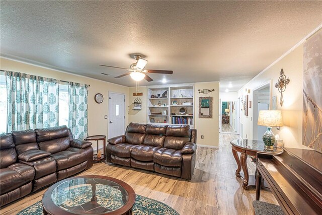 living room featuring light wood-type flooring, crown molding, a textured ceiling, and ceiling fan