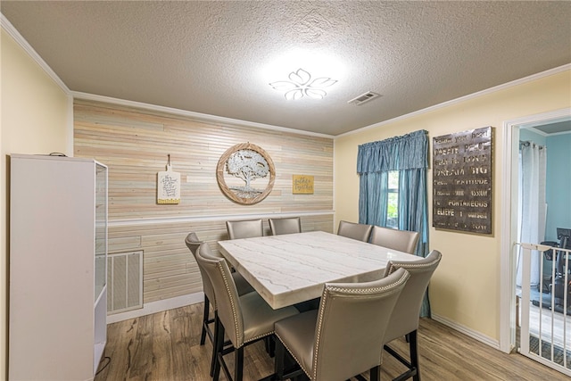 dining space featuring a textured ceiling, wooden walls, and hardwood / wood-style floors