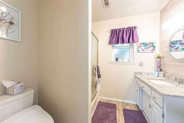 bathroom with a textured ceiling, a shower with door, hardwood / wood-style floors, vanity, and toilet