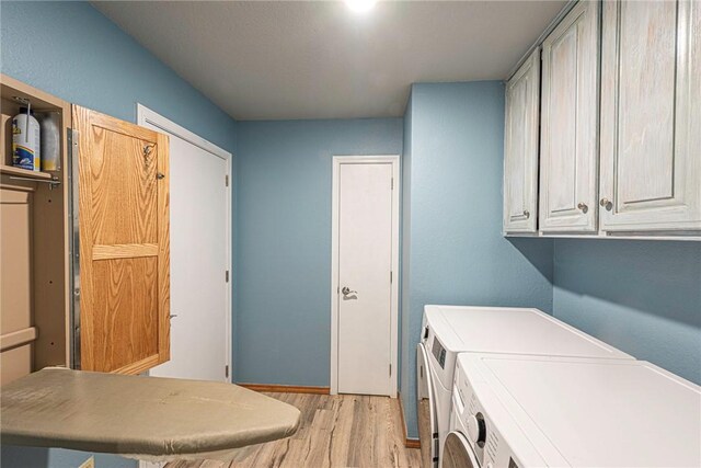 clothes washing area featuring cabinets, light wood-type flooring, and separate washer and dryer