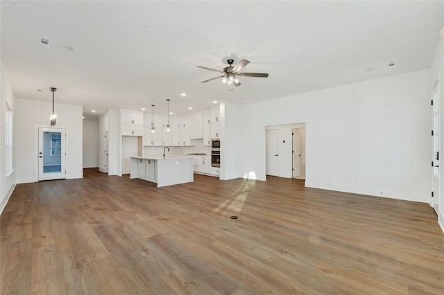 unfurnished living room with sink, light hardwood / wood-style flooring, and ceiling fan