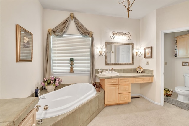 bathroom with vanity, tiled bath, and toilet