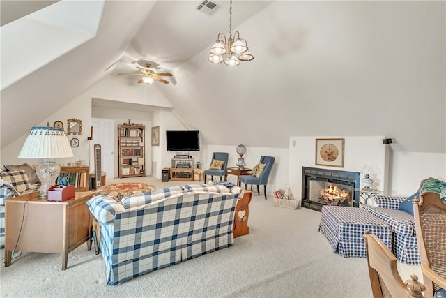 carpeted living room with ceiling fan with notable chandelier, a tile fireplace, and vaulted ceiling