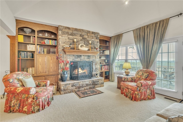 carpeted living room with a stone fireplace and built in shelves