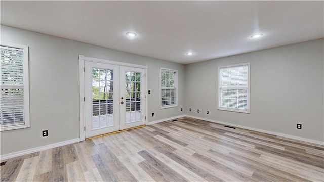 empty room with light wood-type flooring, french doors, and a wealth of natural light