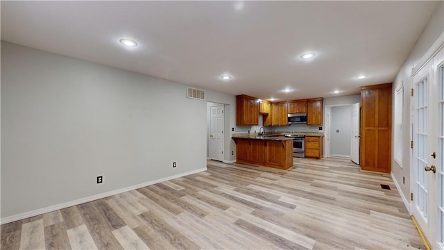 kitchen featuring a breakfast bar, appliances with stainless steel finishes, and light hardwood / wood-style flooring