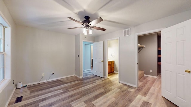 unfurnished bedroom with ceiling fan, light hardwood / wood-style floors, a spacious closet, connected bathroom, and a closet