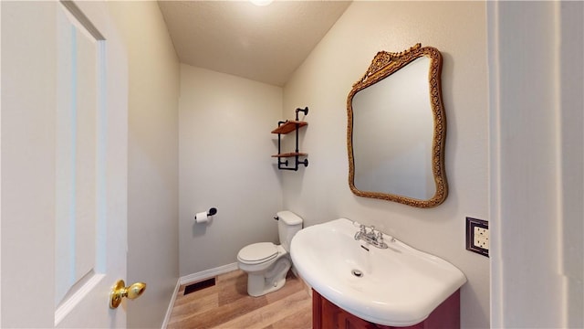 bathroom with toilet, sink, and hardwood / wood-style floors