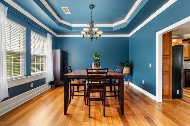 dining room with light hardwood / wood-style floors, crown molding, and a tray ceiling