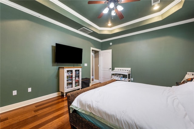 bedroom with ceiling fan, ornamental molding, a tray ceiling, and hardwood / wood-style floors