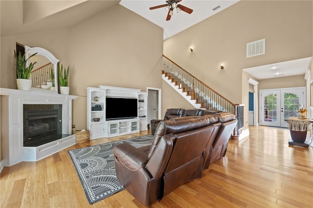 living room with light hardwood / wood-style flooring, french doors, high vaulted ceiling, and ceiling fan