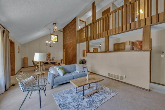 carpeted living room featuring ceiling fan with notable chandelier and high vaulted ceiling