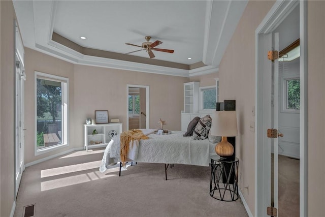 carpeted bedroom featuring a tray ceiling and ceiling fan