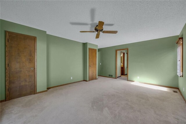 empty room with ceiling fan, light carpet, and a textured ceiling