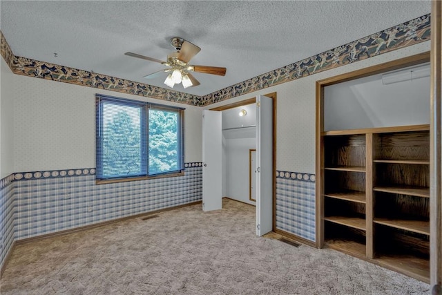 unfurnished bedroom featuring ceiling fan, light colored carpet, and a textured ceiling