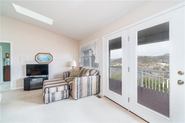 carpeted living room with lofted ceiling with skylight