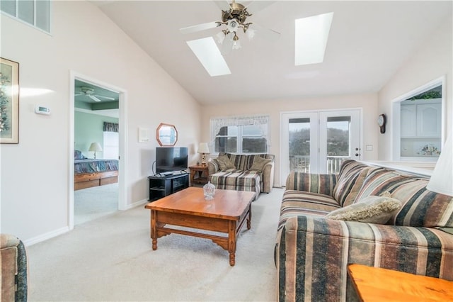 carpeted living room with ceiling fan and lofted ceiling with skylight