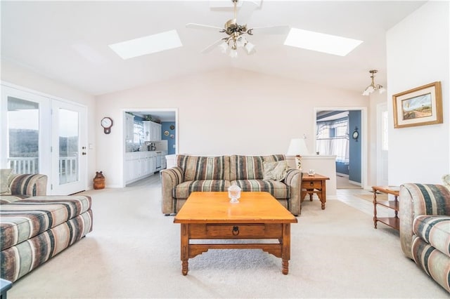 carpeted living room with lofted ceiling with skylight and ceiling fan