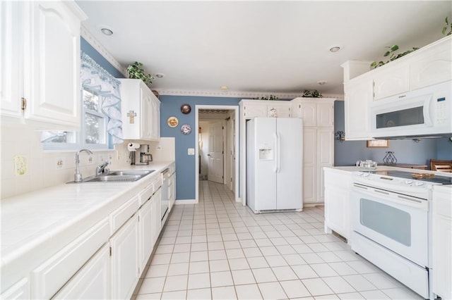 kitchen with sink, white appliances, tile counters, white cabinets, and light tile patterned flooring