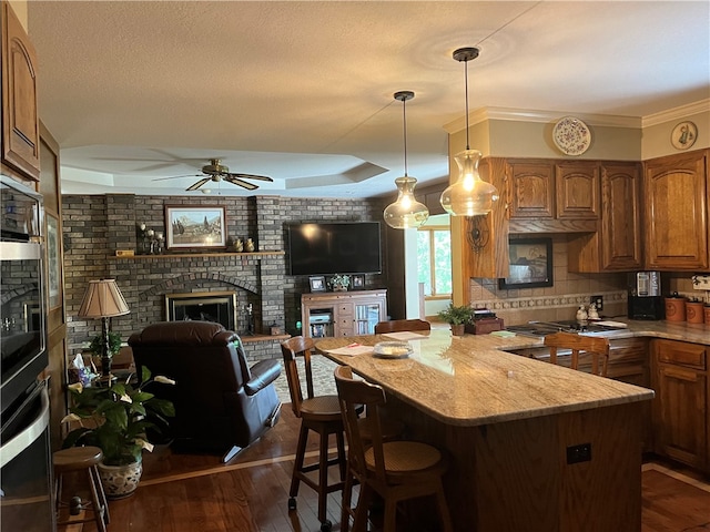 kitchen with ceiling fan, dark hardwood / wood-style floors, a fireplace, and a breakfast bar area